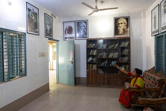 Aloka Kushari, a descendant of the Kushari family linked to Rabindranath Tagore, gestures toward portraits and books inside the Rabindra Memorial Collection at Pithabhog village in Khulna, Bangladesh. Photo: Nayem Ali