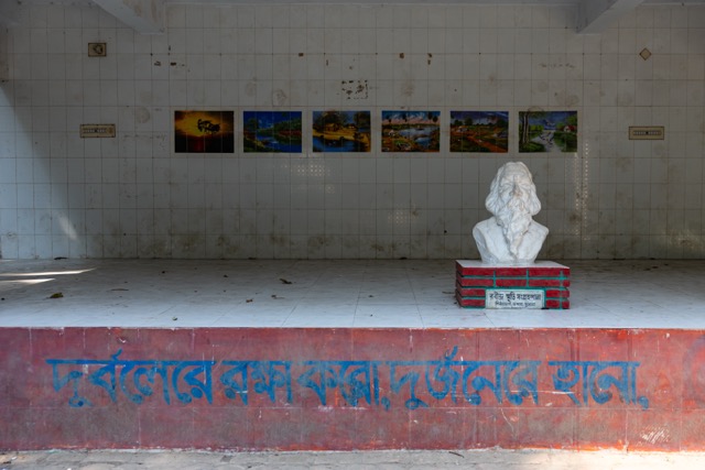 A bust of Rabindranath Tagore stands on a low platform in front of a tiled wall lined with landscape murals at the Rabindra Memorial complex in Pithabhog village in Khulna, Bangladesh. Photo: Nayem Ali