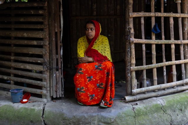 Aloka Kushari, from the seventeenth generation of Rabindranath Tagore’s Kushari descendants, sits in the doorway of her bamboo-and-wood home in Pithabhog village in Khulna, Bangladesh, balancing her work at the memorial with the family’s small poultry business. Photo: Nayem Ali